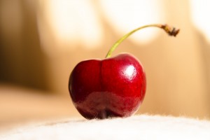 a ripe cherry on white carpet macro background