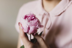 girl-holding-pink-peony-flower-heart-in-front-of-her-chest